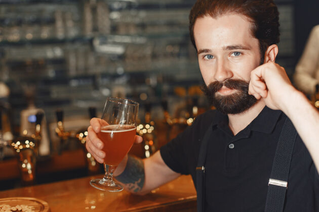 液体一个留着胡子的男人站在吧台旁 喝着酒杯里的酒西装肖像威士忌