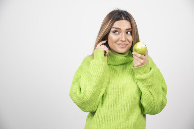 肖像穿着绿色t恤的年轻女子手里拿着一个苹果举行营养用餐