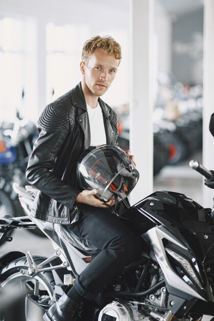 客户一个男人在摩托店里选摩托车一个穿黑夹克的男人一个戴头盔的男人展示服务多样性