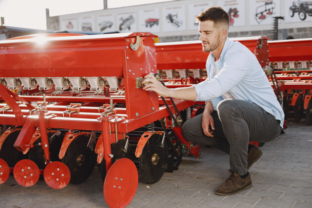 户外农艺师选择一个新的播种机在商店的户外地面上的人农业机械运输收割机展示