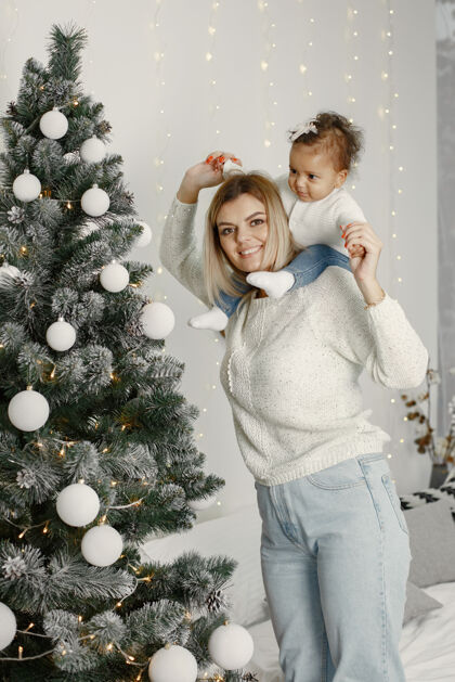 毛衣人们在为圣诞节做准备母亲在和女儿玩耍一家人在节日的房间里休息孩子穿着毛衣花环小国际