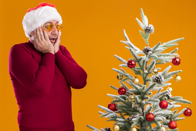 站着中年男子戴着圣诞老人帽 深红色高领毛衣 戴着黄色眼镜年龄看深色