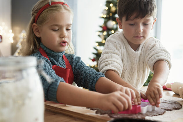甜点两个孩子切姜饼桌子圣诞树人
