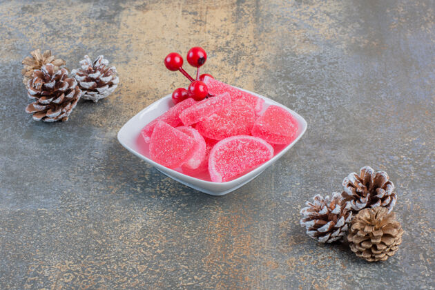 松果一个白色的盘子里装满了红色果冻糖果和松果高质量的照片果冻多汁美味