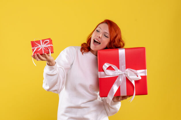 人黄色墙壁上年轻女子拿着圣诞礼物的正面图微笑微笑礼物