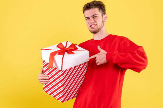 颜色正面图穿红色衬衫的年轻男性 盒子里有礼物年轻男性礼物