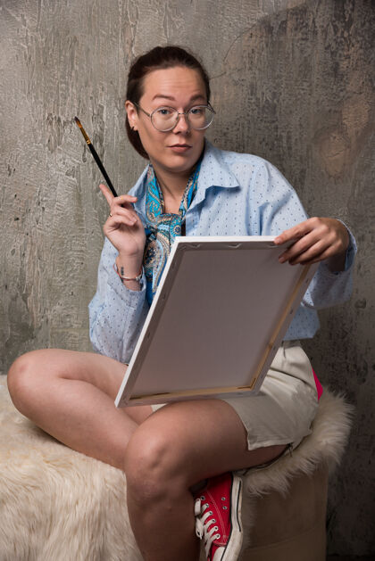 大理石坐在大理石背景上拿着画布和画笔的女人女士画布画笔