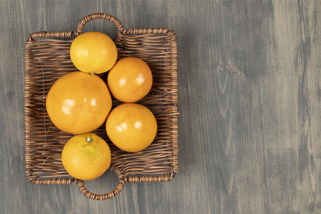 成熟一个柳条篮子装满新鲜的橘子放在木桌上高质量的照片篮子吃橘子