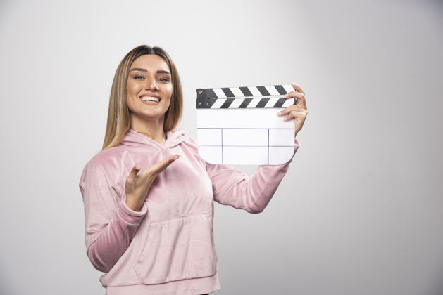 拍摄穿着粉色运动衫的金发女士拿着一块空白的隔板 摆出自然的姿势人电影制作视频生产