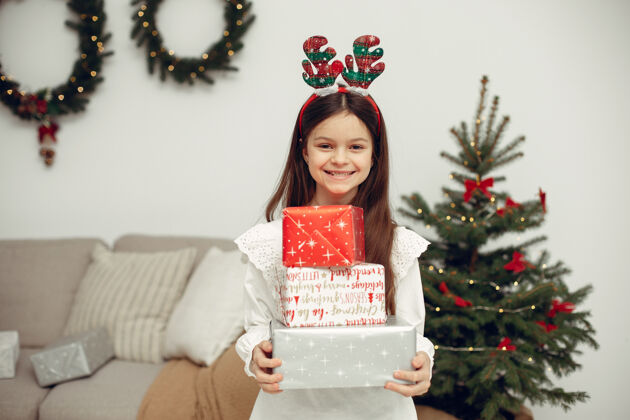 灯穿白色毛衣的孩子坐在圣诞树旁的女儿毛衣肖像年轻