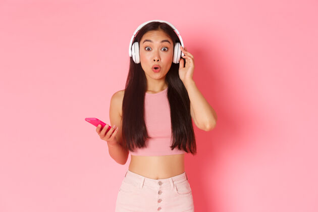 耳机一个戴着耳机听音乐的富有表情的年轻女子休闲应用程序女人
