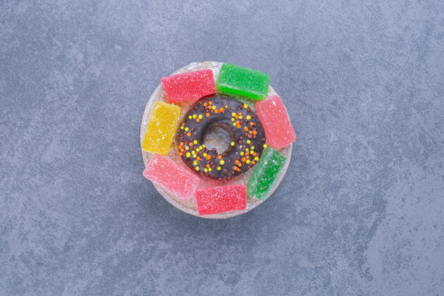 美味美味的甜甜圈和果冻糖果在灰色的表面糕点巧克力果冻