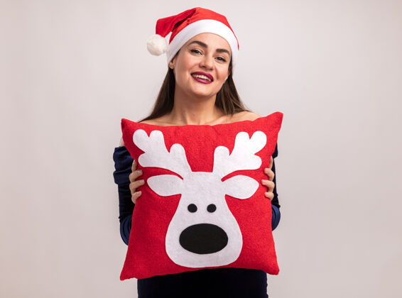 呼啦圈微笑着的年轻漂亮的女孩穿着蓝色的裙子和圣诞发箍抱着圣诞枕头隔离在白色的背景上圣诞节枕头年轻