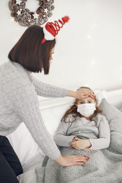 床儿童中有冠状病毒母亲带着女儿孩子躺在床上戴着医用口罩的妇女发烧小流感
