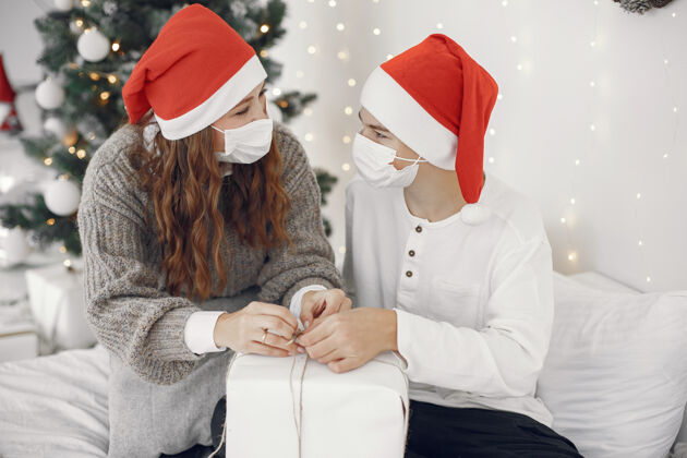 盒子为圣诞节做准备的人冠状病毒主题妈妈和儿子玩穿白毛衣的男孩童年毛衣小