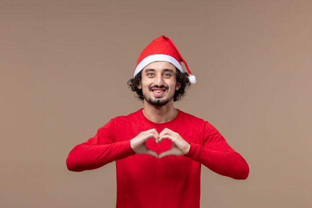 微笑正面图：年轻人在圣诞节的棕色背景下送出爱成人情感男性
