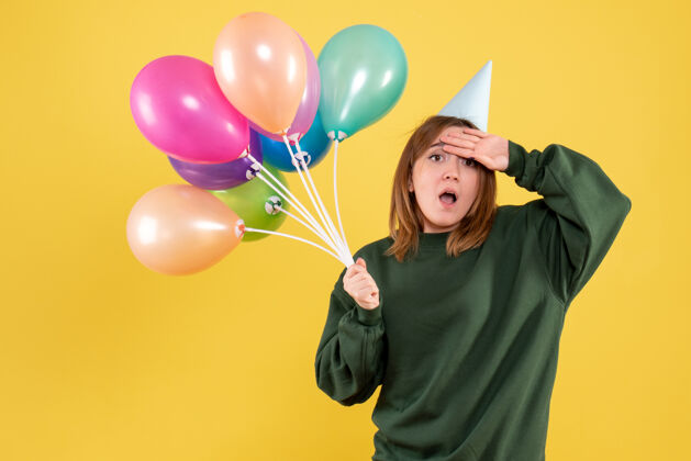 女性正面图：带着彩色气球的年轻女性乐趣多彩庆祝