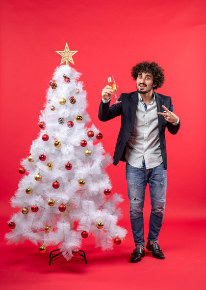 圣诞庆祝新年快乐的年轻人举着一杯酿酒的胜利手势酒树年轻人