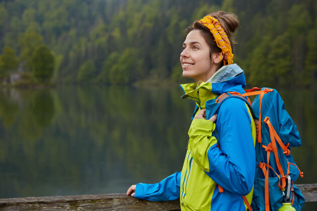 徒步旅行在湖边和绿林边漫步的快乐活跃的女性的户外景色沉思平静背包