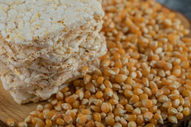 脆的脆面包和生玉米籽放在木片上种子生的零食