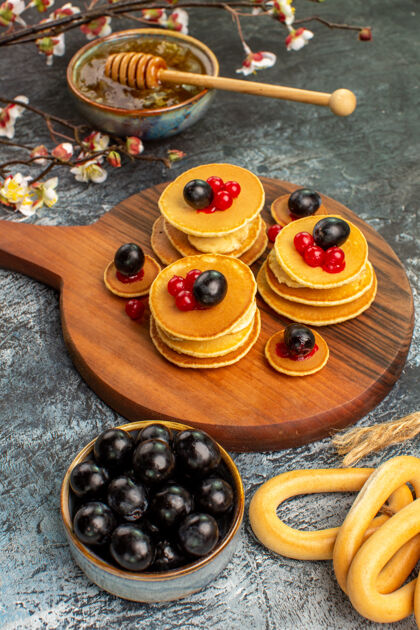 配料环形曲奇的垂直视图水果煎饼蜂蜜在碗里 黑樱桃在灰色的桌子上棕色橄榄色甜味