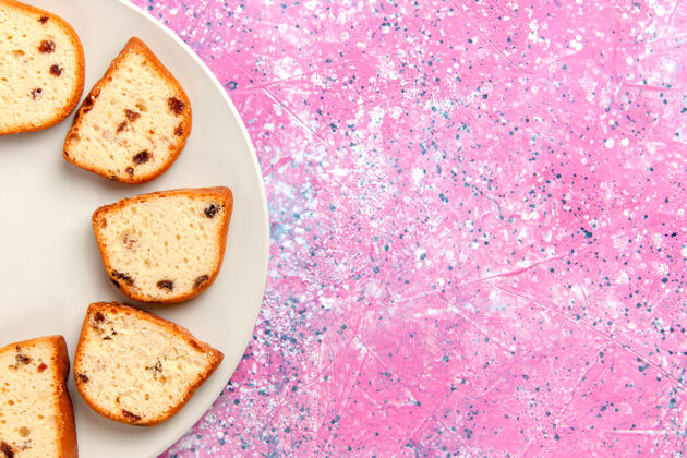 生的顶视图蛋糕片与葡萄干内盘粉红色背景蛋糕烤甜饼干颜色派糖饼干背景饼干饼干