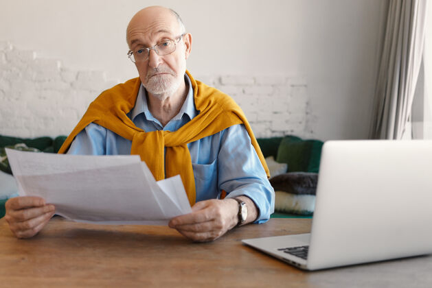 商人电子产品 文书工作 人 职业和生活方式的概念图为时尚的秃头成熟男子与白胡子远程管理业务 阅读文件 使用笔记本电脑桌子老年人男性