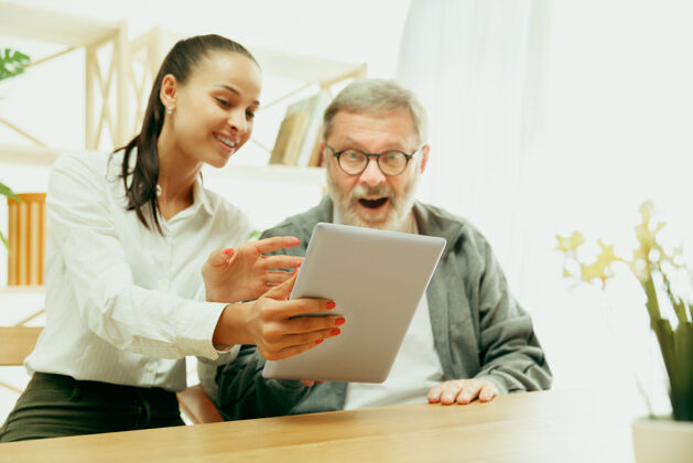 家女儿或孙女花时间和爷爷或老人在一起家庭或父亲节 情绪和幸福在家里的生活方式肖像女孩照顾爸爸使用平板电脑看孙女老年人