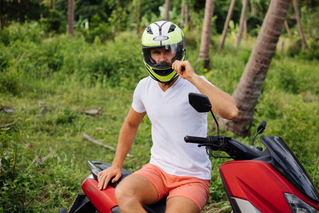 生活在热带丛林地带骑着红色摩托车的壮汉透视旅游人
