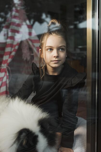 孩子看着窗外的女孩和狗同伴孩子年轻