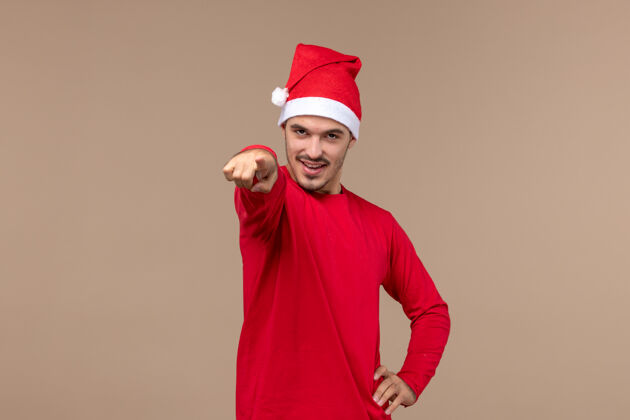 快乐正面图年轻男性指着棕色背景圣诞情感节日男性男性帽子观点