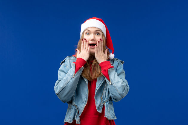 可爱正面图蓝色背景上戴着红帽子的年轻女性新年假期圣诞节女性成人背景