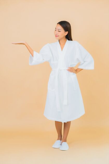 面霜肖像美丽的亚洲年轻女子穿着米色的微笑浴袍健康日本毛巾