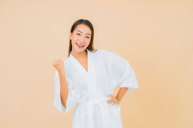 水疗肖像美丽的亚洲年轻女子穿着米色的微笑浴袍保湿面部头部