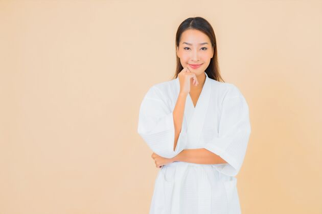 看肖像美丽的亚洲年轻女子穿着米色的微笑浴袍女性清洁清洁