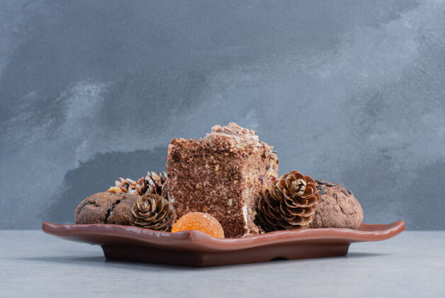 果酱饼干 松果 果冻糖和一块蛋糕放在大理石表面的盘子上糖切片曲奇