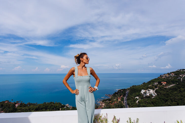 女士在豪华别墅的teracce阳台上 穿着浅蓝色薄荷色的棕褐色高加索女人 可以欣赏到迷人的热带海景海酒店完美