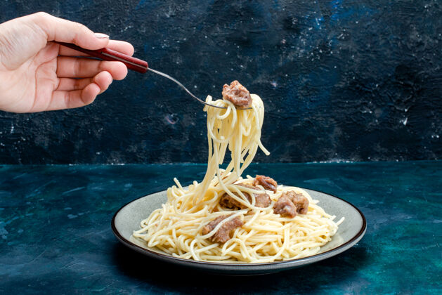 切片前视图煮熟的意大利面食 切肉 在蓝色表面上吃意大利面食 意大利餐 面团肉吃青菜看