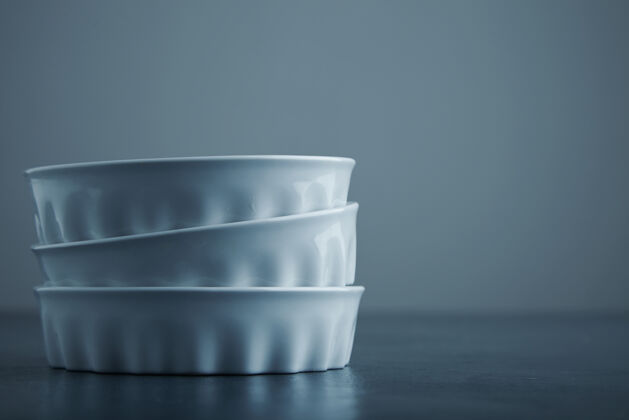 器皿三个陶瓷白色的碗隔离在一边的蓝色乡村的桌子和灰色的背景厨房灰色工艺
