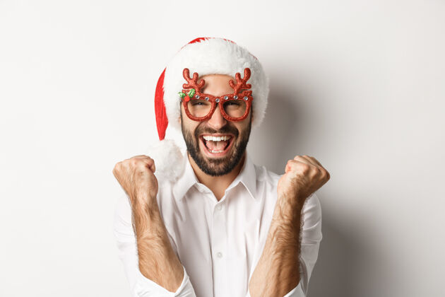 庆祝庆祝圣诞节或新年的特写镜头 戴着圣诞派对眼镜和圣诞帽 欢呼雀跃 站着冬天西装聚会