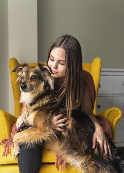狗大流行期间 一个女人和她的狗坐在扶手椅上家庭预防隔离