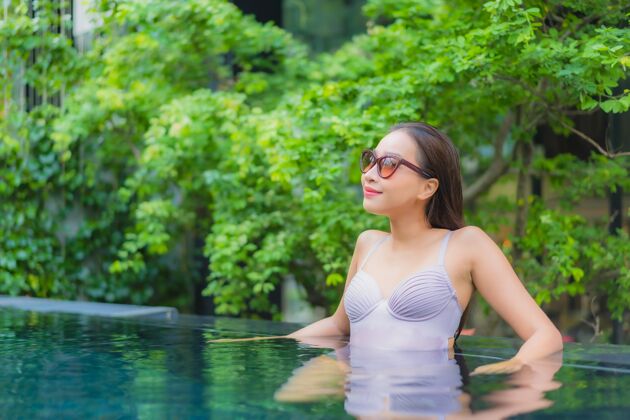 女士肖像美丽的亚洲年轻女子放松微笑休闲在酒店度假村的室外游泳池周围豪华享受天堂