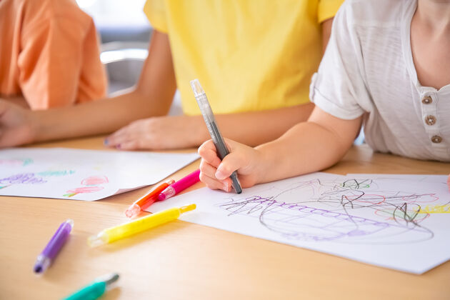 书桌孩子们用钢笔在纸上画画的剪影三个不认识的孩子坐在桌子旁画画选择性聚焦童年 创造力和周末概念儿子玩耍可爱
