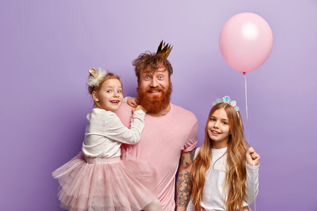成人室内拍摄头戴皇冠的快乐红发男人 手抱美丽的小女儿 在国际儿童节为女儿组织难忘的节日姜家快乐小女人