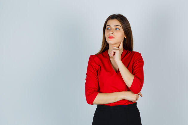 人年轻的女士站在思考的姿势在红色衬衫 裙子和期待沉思抑郁咖啡专业