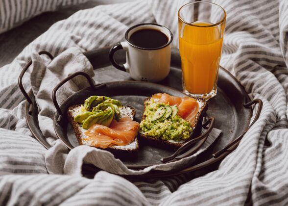 菜高角度的早餐三明治在床上与鳄梨和鲑鱼早餐三文鱼咖啡