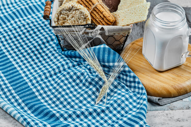 篮子一篮饼干和一罐牛奶放在一张铺着桌布的大理石桌子上木头美味木头