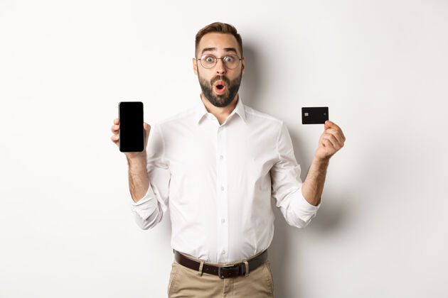成人商务和网上支付笑容可掬的帅哥展示手机屏幕和信用卡 站着男人雇主衬衫