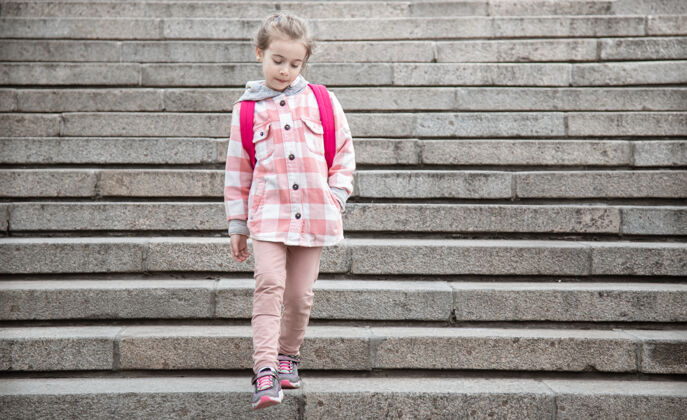 小学生开学和秋天的第一天一个可爱的女孩站在一个宽大的楼梯的背景下孩子女孩行走