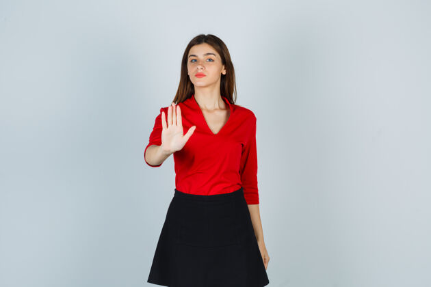 休闲一个穿着红衬衫 黑裙子 表情严肃的年轻女人 正在展示停车标志现代肖像人